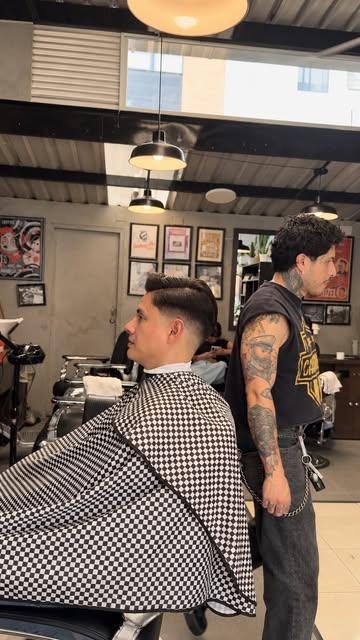 Cliente con capa de cuadros durante un corte en Dapper Men