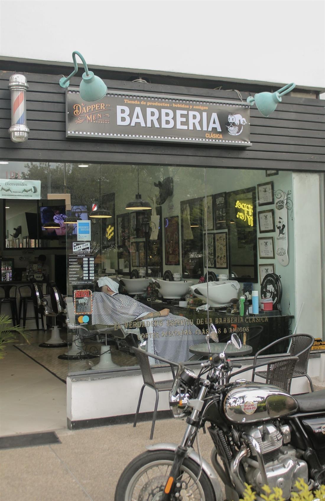 Fachada de Dapper Men Barbers con una moto clásica parqueada al frente